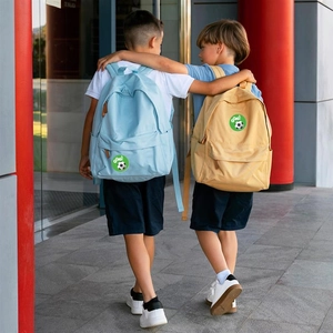 Rear view of children wearing blue and beige soccer backpacks with GOAL print in a hallway