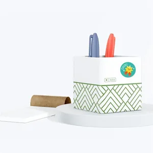 Detail view of square white pen holder with green patterns and yellow 'COOL!' sticker
