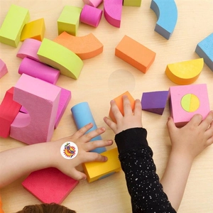 Close-up of a smiling sun cartoon sticker on a child's hand with colorful toy blocks