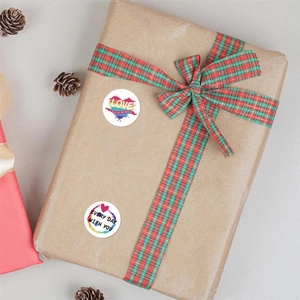 Detail of round heart stickers with 'Love' text on gift box with plaid ribbon decoration