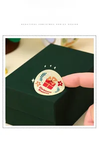 Detail of a round Christmas Presents sticker being applied to a festive gift box