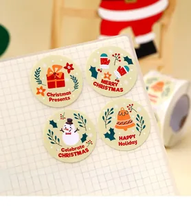 Macro shot of four round Merry Christmas seal stickers on a grid notebook paper