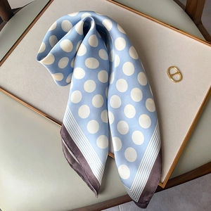 Detail of light blue polka dot silk scarf with striped border on display stand