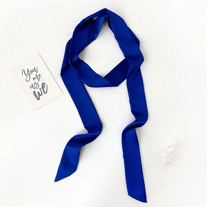 Detail of royal blue silk ribbon scarf showing luxurious satin texture and angled ends