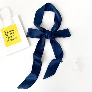 Detail of dark blue satin skinny scarf tied in a bow showing smooth silk texture