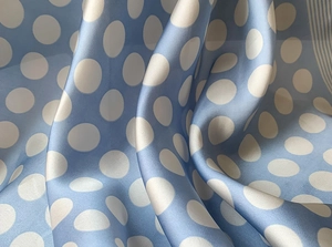 Detailed view of light blue satin silk scarf with white polka dots and striped hem