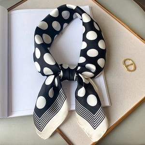 Detail of a silk scarf with black polka dots and striped edges on a white magazine