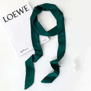 Close-up of emerald green satin skinny scarf with smooth texture and neat stitching