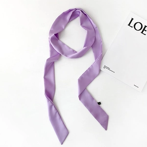 Detail shot of a lavender satin skinny scarf with diagonal ends and brand tag on white background