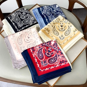Detailed view of paisley silk scarves in five colors including navy, yellow and pink
