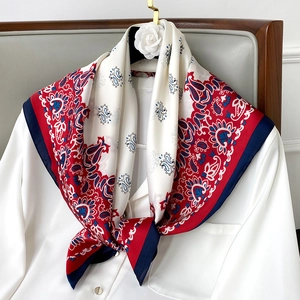 Detail of paisley silk scarf in red and navy blue tied on a white shirt collar