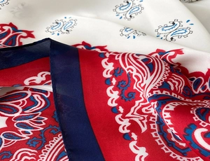 Macro shot of paisley silk scarf showing smooth satin texture and rolled hem details