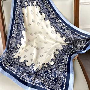Macro detail of the paisley pattern and satin finish on the silk scarf draped on a chair