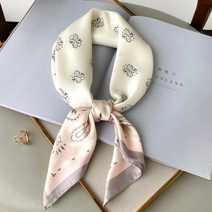 Elegant silk scarf with paisley patterns tied in a knot on a decorative tray