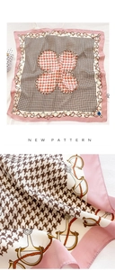Detail of pink silk square scarf with brown houndstooth pattern and clover design