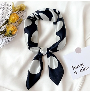 Detailed close-up of a knotted black and white polka dot silk scarf with smooth texture