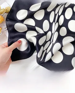 Detail of hand-rolled edges on a black silk scarf with large white polka dots pattern