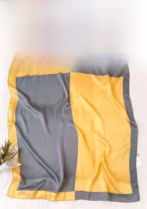 Dettaglio foulard geometrico in seta color-block giallo e grigio con finitura satinata