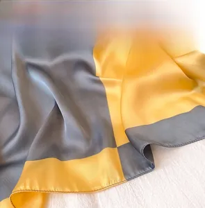 Dettaglio macro di foulard in seta satinata grigio e giallo con finiture di cucitura precise