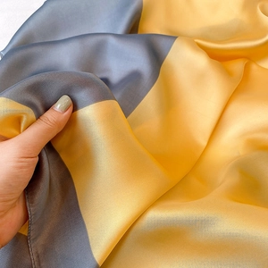 Dettaglio ravvicinato della trama setosa con design color block grigio e giallo