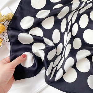Close-up of lightweight silk scarf fabric with classic white polka dots on black