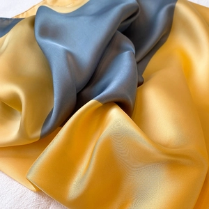 Dettaglio di sciarpa in raso di seta con eleganti blocchi di colore oro e grigio blu
