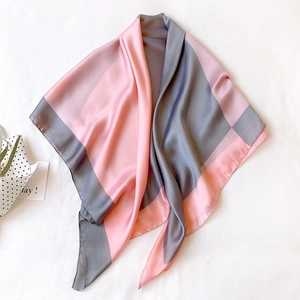 Dettaglio di un foulard quadrato in raso di seta rosa e grigio con trama lucida