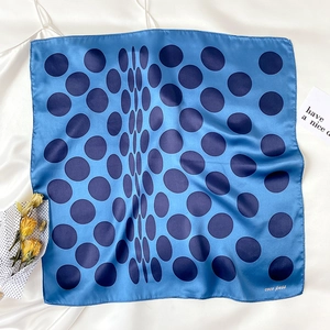 Detail shot of sky blue silk square scarf with large navy polka dots and brand logo