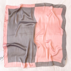 Dettaglio di un foulard quadrato di seta rosa e grigio con trama liscia e bordi arrotolati