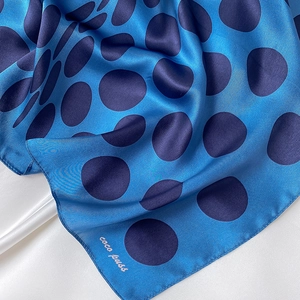 Macro detail of silk polka dot scarf showing soft sheen and neat rolled hem edges