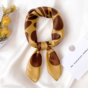 Elegant giraffe print silk square scarf with Kuss logo on white satin background