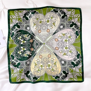 Detail of green silk scarf featuring intricate floral heart patterns and hand-rolled edges