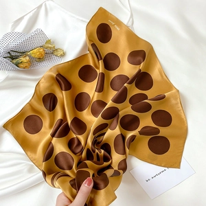 Macro shot of mustard yellow silk scarf with large brown polka dots and glossy texture