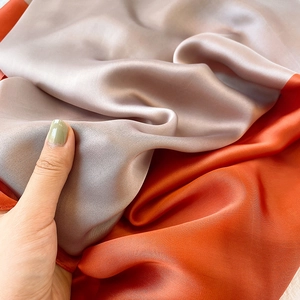 Dettaglio di un elegante foulard in raso di seta terracotta e grigio argento lucido