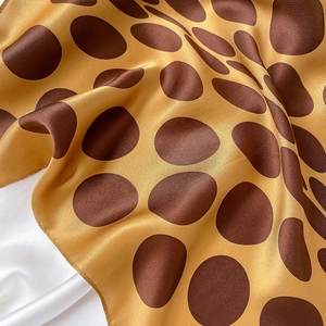 Detail of silk scarf showing brown polka dots on yellow satin with elegant soft drapes