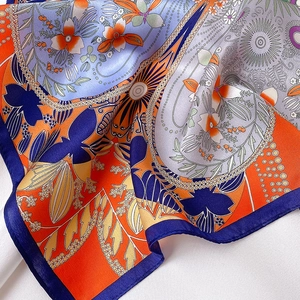 Close-up of printed silk scarf with floral patterns and vibrant blue and orange hues