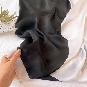 Dettaglio di un foulard in seta bianco e nero con trama traslucida e bordi arrotolati a mano