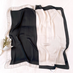 Dettaglio di un foulard di seta bianco e nero con una trama liscia e finitura satinata
