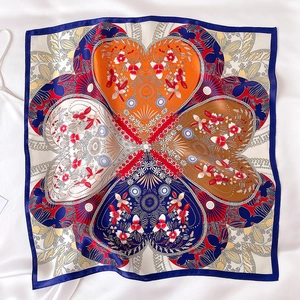 Close-up of silk scarf showing four colorful heart patterns and fine texture detail