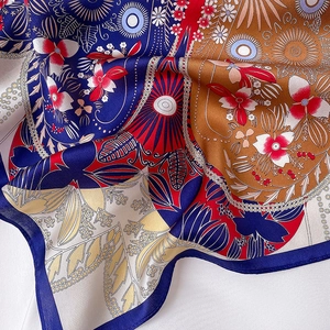 Macro view of patterned silk square scarf showing detailed ethnic floral prints and texture