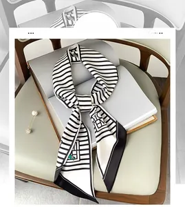 Detail of a black and white striped skinny silk scarf on a book with a pearl brooch