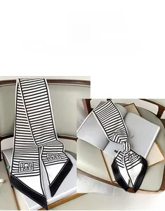 Detail of black and white striped silk skinny scarf tied on a magazine showing pointed tip