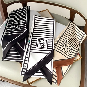 Detailed shot of striped silk-like twilly scarves in geometric patterns on a gold tray