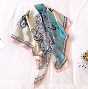 Macro detail of silk-feel square scarf featuring blue paisley patterns and contrast borders