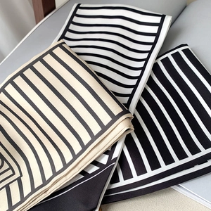 Close-up of geometric striped silk scarves in black, white, and beige color options