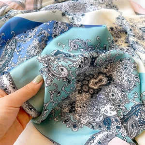 Detailed view of paisley print silk scarf in sky blue and mint green with rolled hem