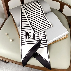 Detail of a geometric black and white striped twilly scarf with logo on a magazine