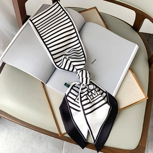 Elegant black and white striped long silk scarf with letter accent on a vintage book