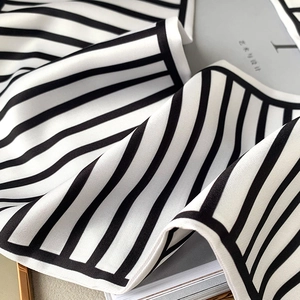 Detail shot of elegant black and white striped silk scarf with smooth draped texture