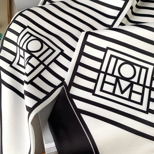 Detailed view of the black and white geometric striped silk scarf with logo on twill fabric